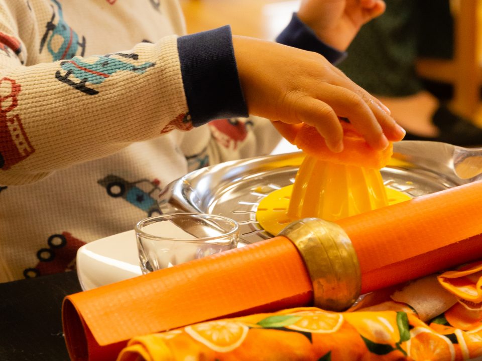Child juicing an orange independently