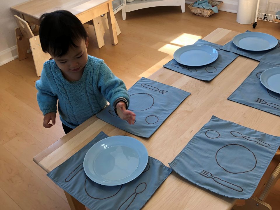 Toddler setting the table for lunch