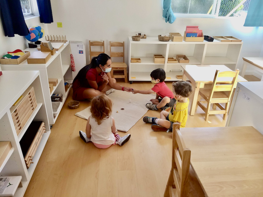 Montessori classroom with teacher guiding primary students