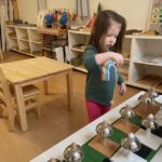 Primary Child working on Sensorial using the Montessori Bells allows learning volume, pitch and lay the foundation for learning music at La Jolla Montessori School!