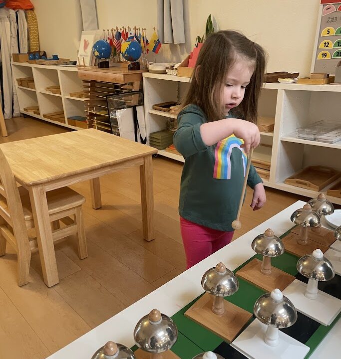 Primary Child working on Sensorial using the Montessori Bells allows learning volume, pitch and lay the foundation for learning music at La Jolla Montessori School!
