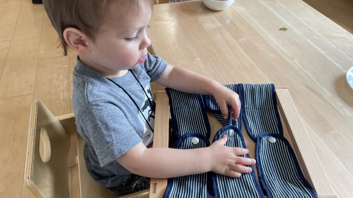 Best Age To Start Preschool. Toddler learning how to snap buttons.