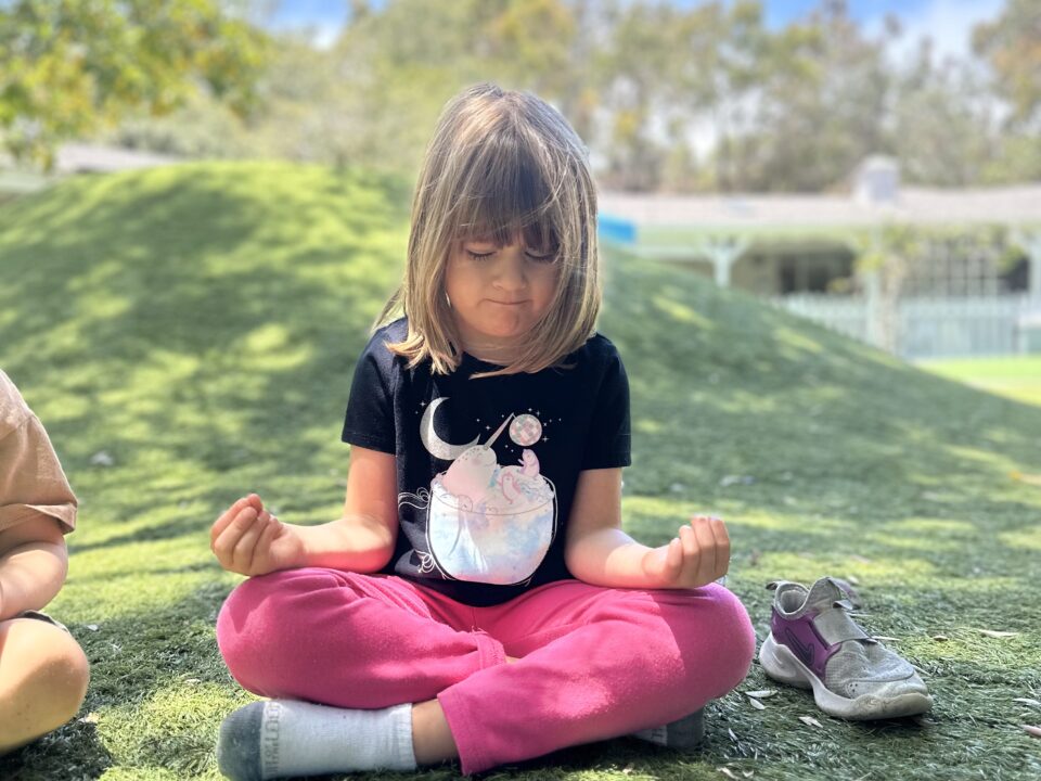 Niño Montessori meditando mientras hace yoga para apoyar la salud y el bienestar en La Jolla Montessori School