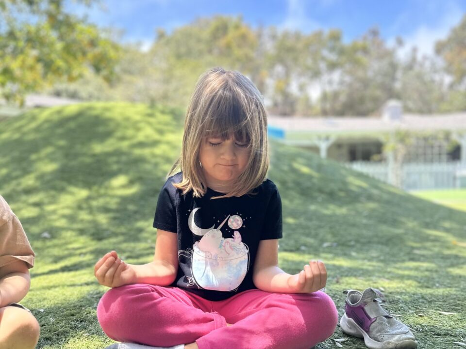 Montessori child meditating while doing yoga to support health and wellness at La Jolla Montessori School