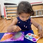 Montessori Child painting and relaxing at La Jolla Montessori School