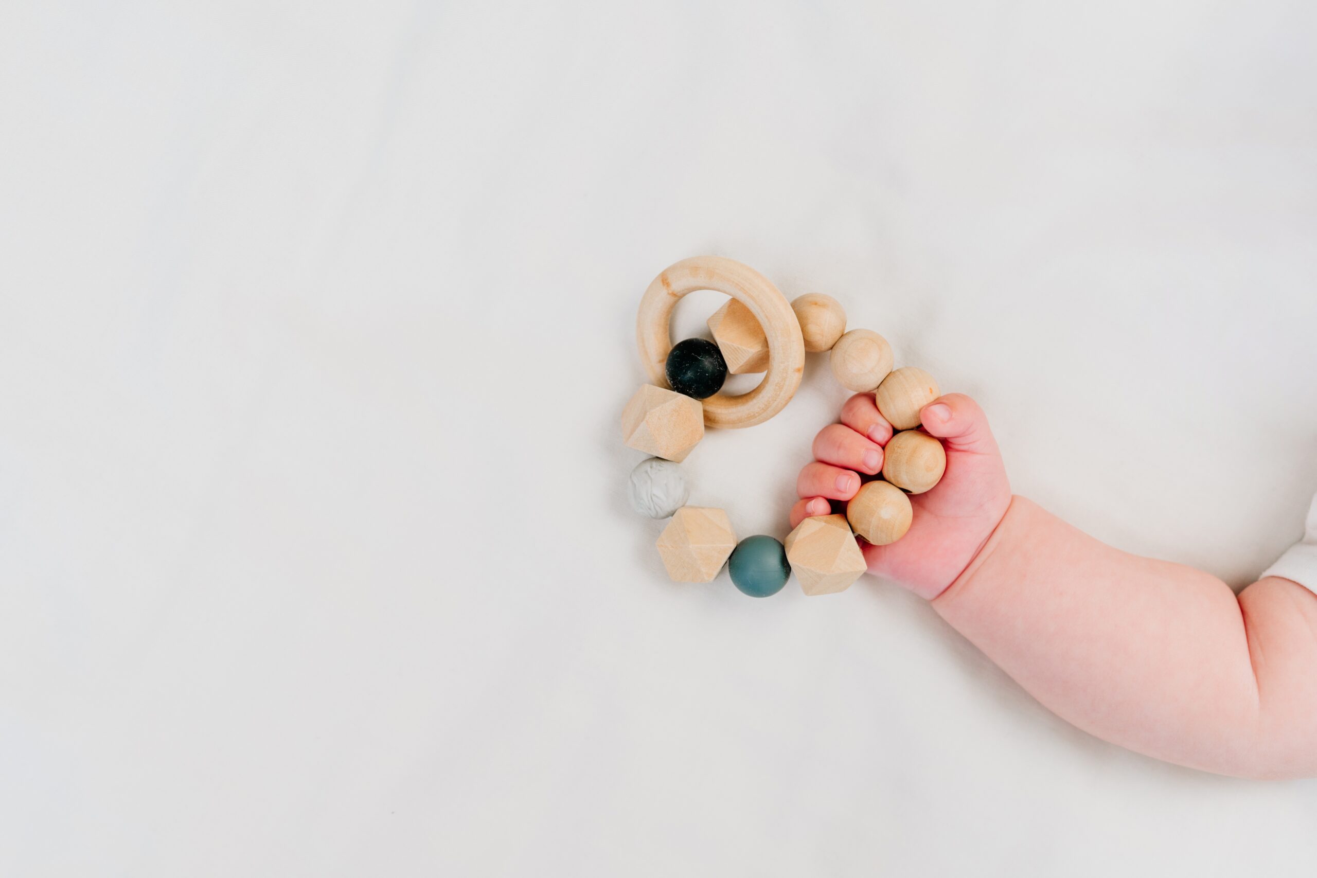 Infant Nido Program at La Jolla Montessori School showing a baby's hand and a wooden teething toy
