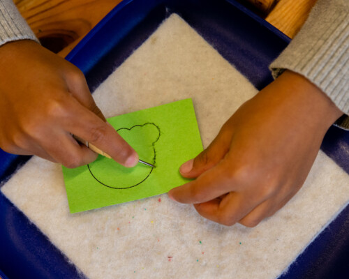 child doing art poking holes in outline