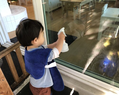 Toddler cleaning a window independently