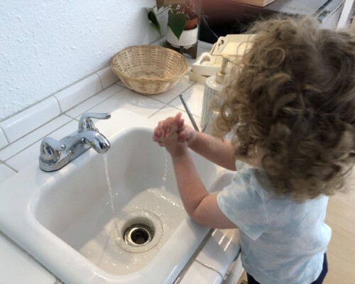 Toddlers learn how to wash their hands with a child size sink
