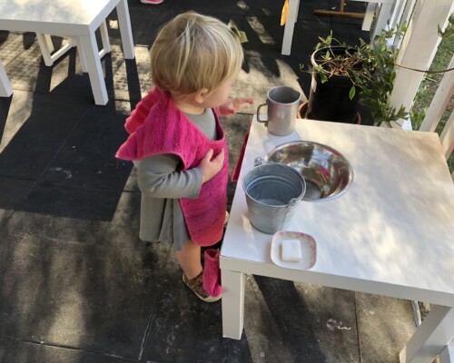 Toddler washing hands independently in a Montessori preschool
