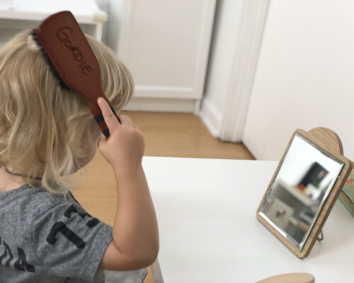 Toddler independently brushing his hair at La Jolla Montessori School