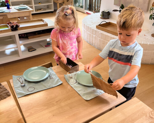 Toddler setting the table for lunch at La Jolla Montessori school