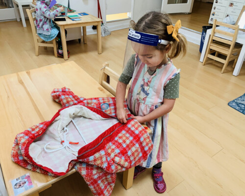 Girl learning how to use a zipper independently