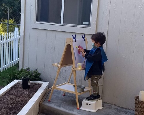 Toddler painting outside independently