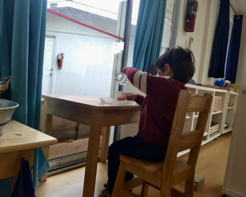 Toddler pouring water into small glass independently