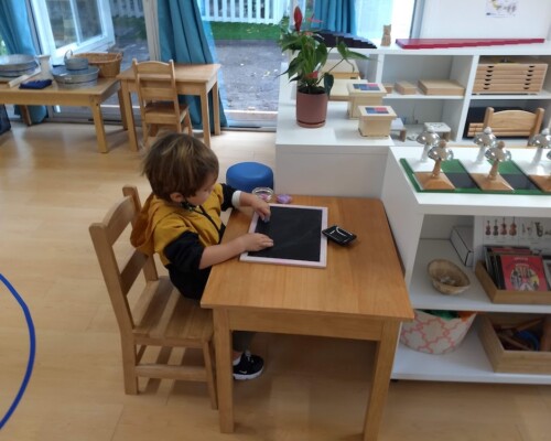 Toddler writing with chalk and blackboard independently