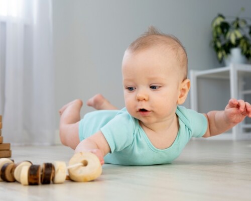 cute infant baby crawling on the floor at home, playing with colorful balls